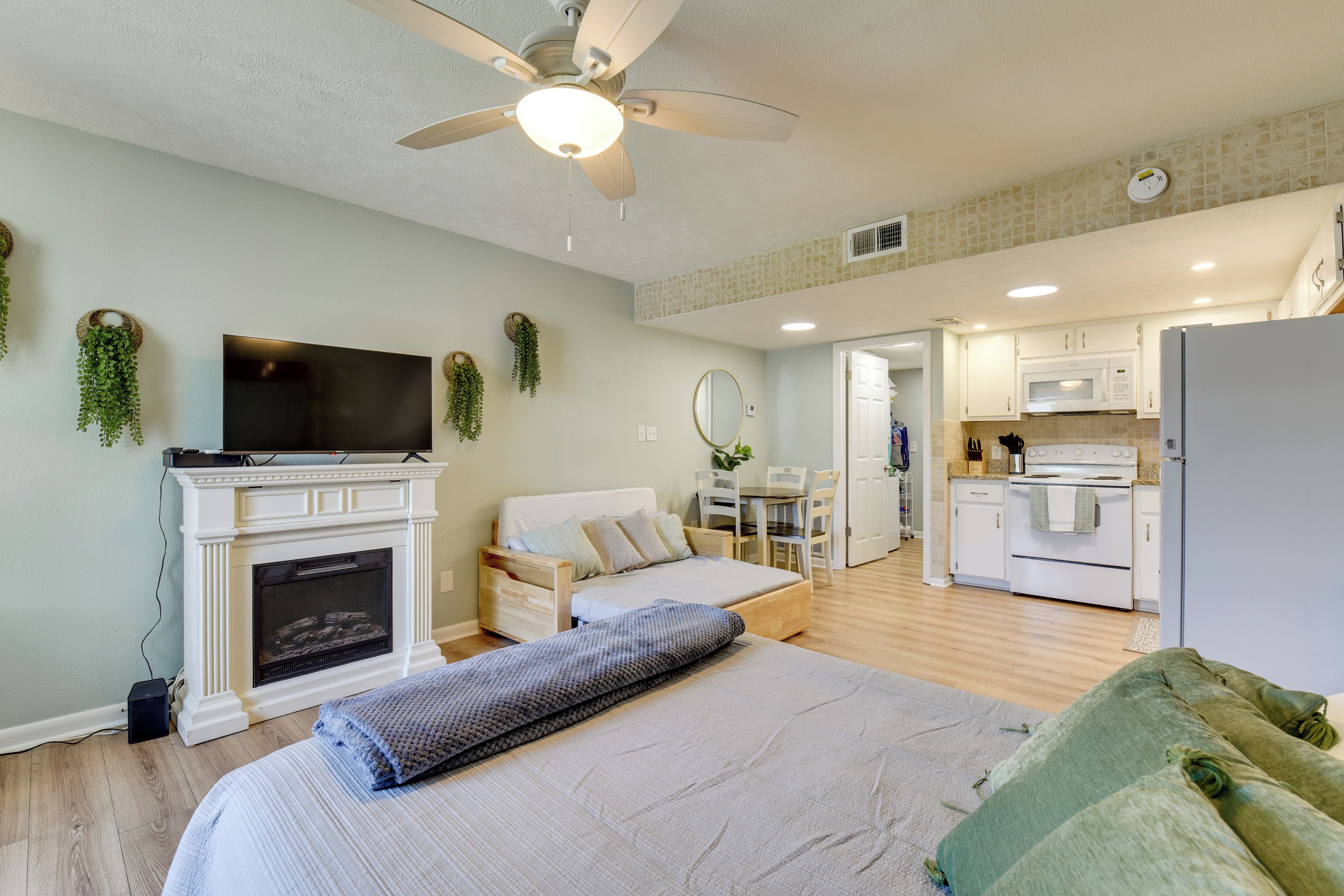 A bedroom with a bed, a television, a fireplace, and a ceiling fan.