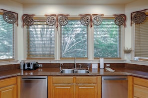 A kitchen with a built-in dishwasher, a double sink, and a window with blinds.