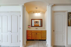 A bathroom with a vanity, a mirror, and two doors.