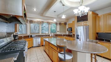 A modern kitchen with a central island, stainless steel appliances, and wooden cabinetry.