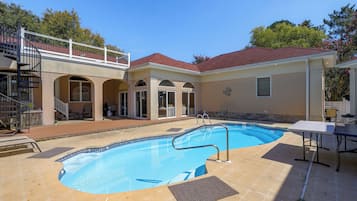 A residential property with a swimming pool, a covered patio, and a two-story house with a balcony.