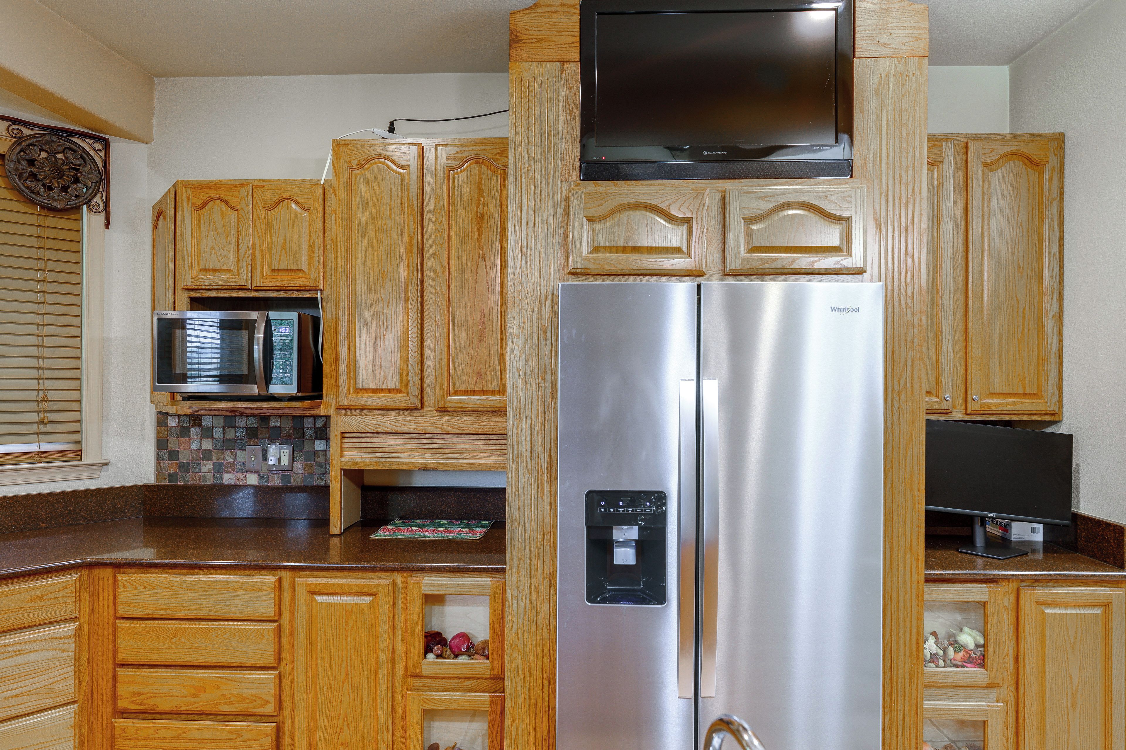 A kitchen with wooden cabinets, a stainless steel refrigerator, a microwave, and a water dispenser.