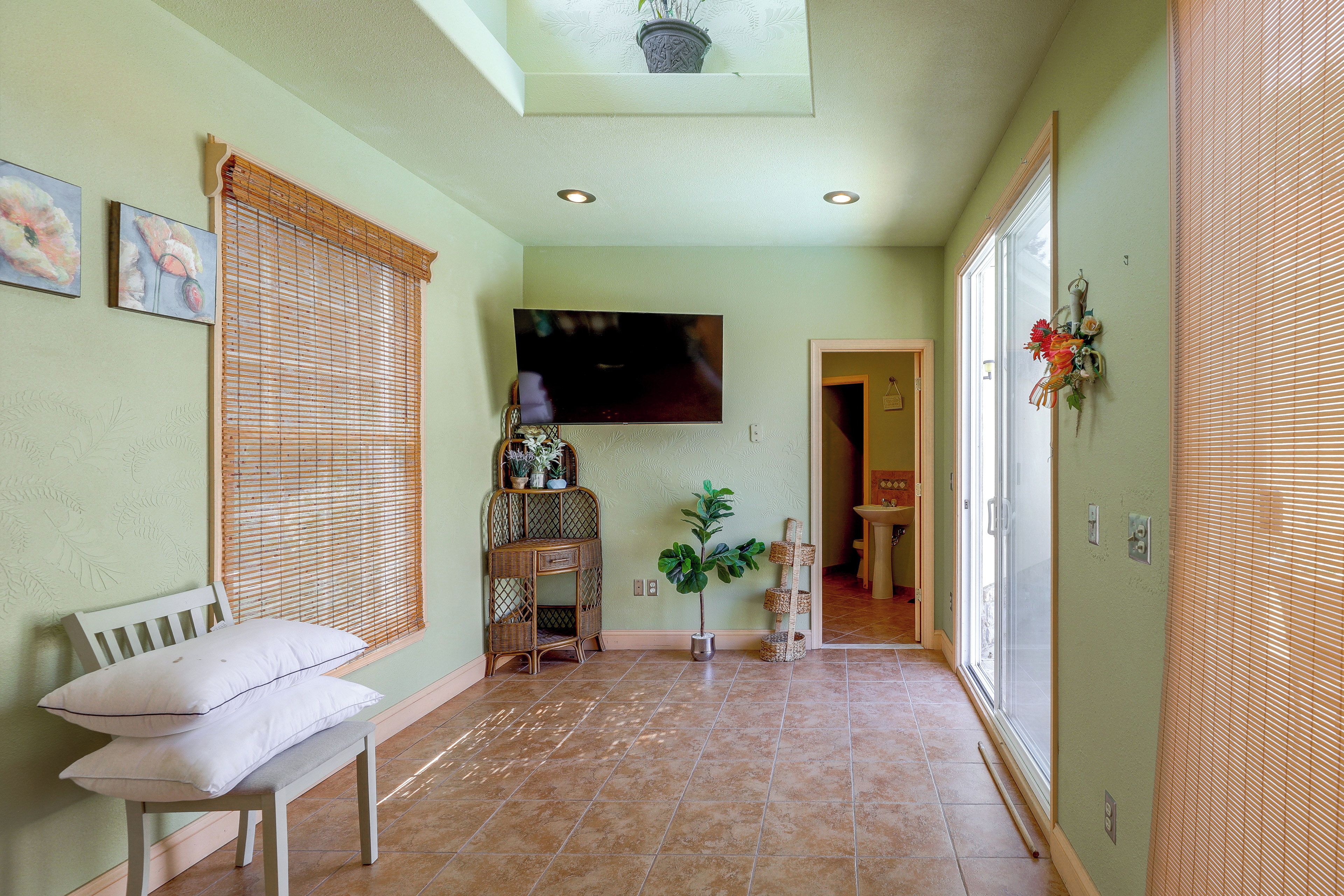 A hallway with a bench, a flat-screen TV mounted on the wall, and a potted plant.