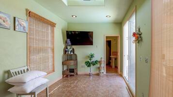A hallway with a bench, a flat-screen TV mounted on the wall, and a potted plant.