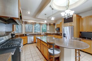 A modern kitchen with a central island, stainless steel appliances, and wooden cabinetry.