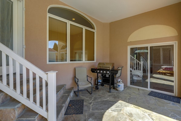 A covered outdoor area with a barbecue grill, a chair, and a staircase leading to a door. - Luxury Home 3 Mi to Bethany Beach Boardwalk! (Ocean View)