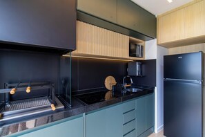 Eine moderne Küche mit einem schwarzen Kühlschrank, einer Mikrowelle und einem Einbauofen.