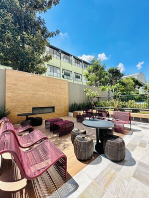 Eine Außenpatio mit Sitzgelegenheiten, einem Tisch und einer Wand.