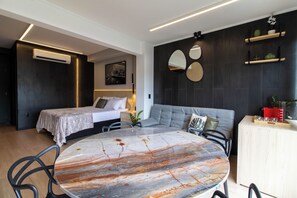 Una camera d'hotel moderna con un letto, un divano, un tavolo da pranzo e un angolo cottura.