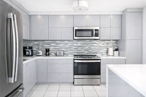 Een moderne keuken met roestvrijstalen apparatuur, een betegelde spatwand en een strak, minimalistisch design.