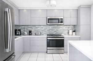 Una cocina moderna con electrodomésticos de acero inoxidable, salpicadero de azulejos y un diseño limpio y minimalista.