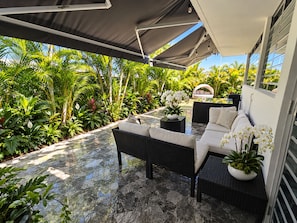 An outdoor patio with a sofa and table, surrounded by lush tropical plants and a clear view of the sky. - Exclusive Beachfront Retreat With Private Pool in Loíza, Puerto Rico (Loiza)