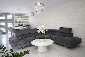 A modern living room with a grey sectional sofa, a white marble coffee table, and a chandelier. - Exclusive Beachfront Retreat With Private Pool in Loíza, Puerto Rico (Loiza)