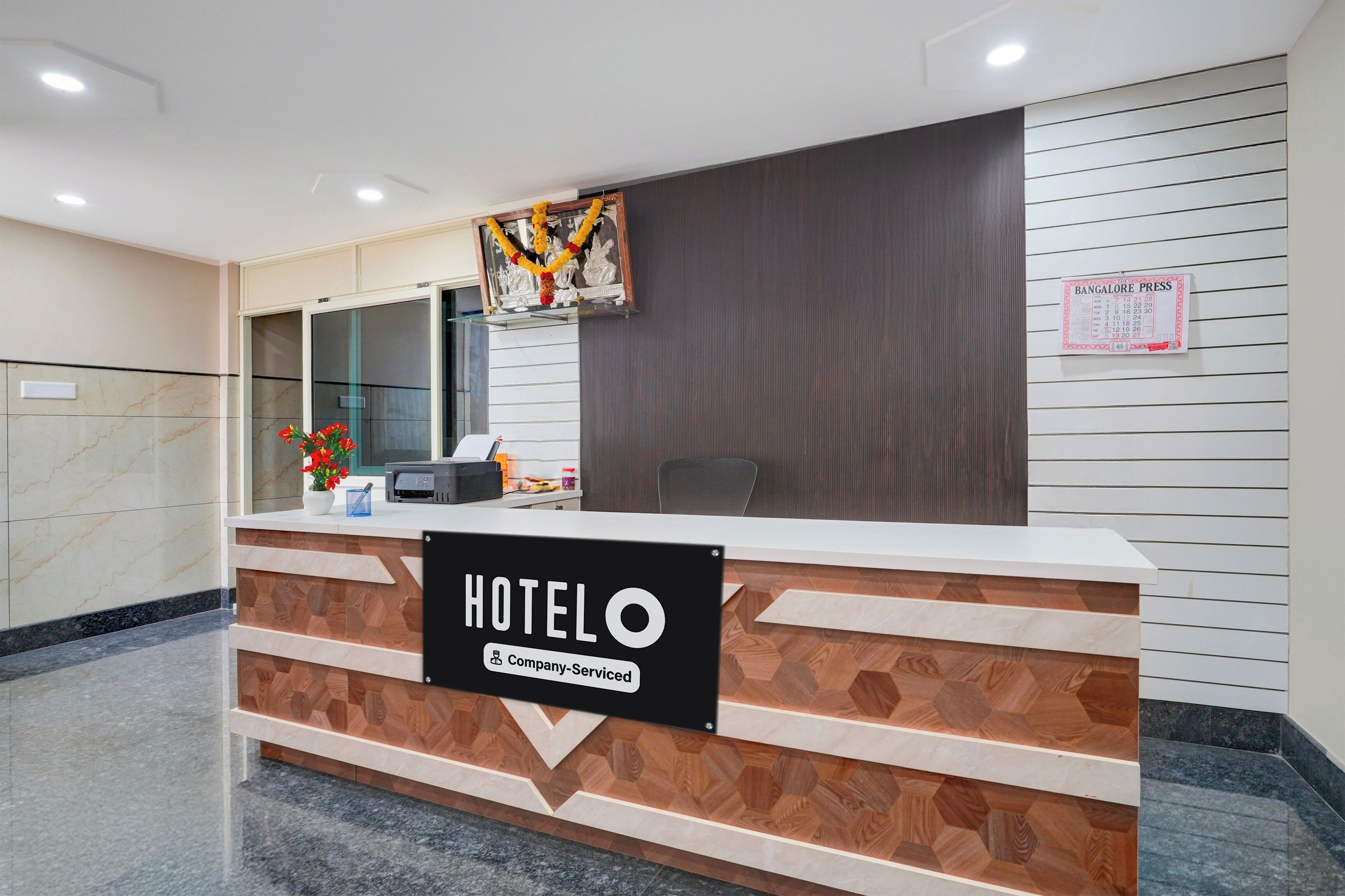 A hotel reception desk with a sign indicating it is a company-serviced hotel.