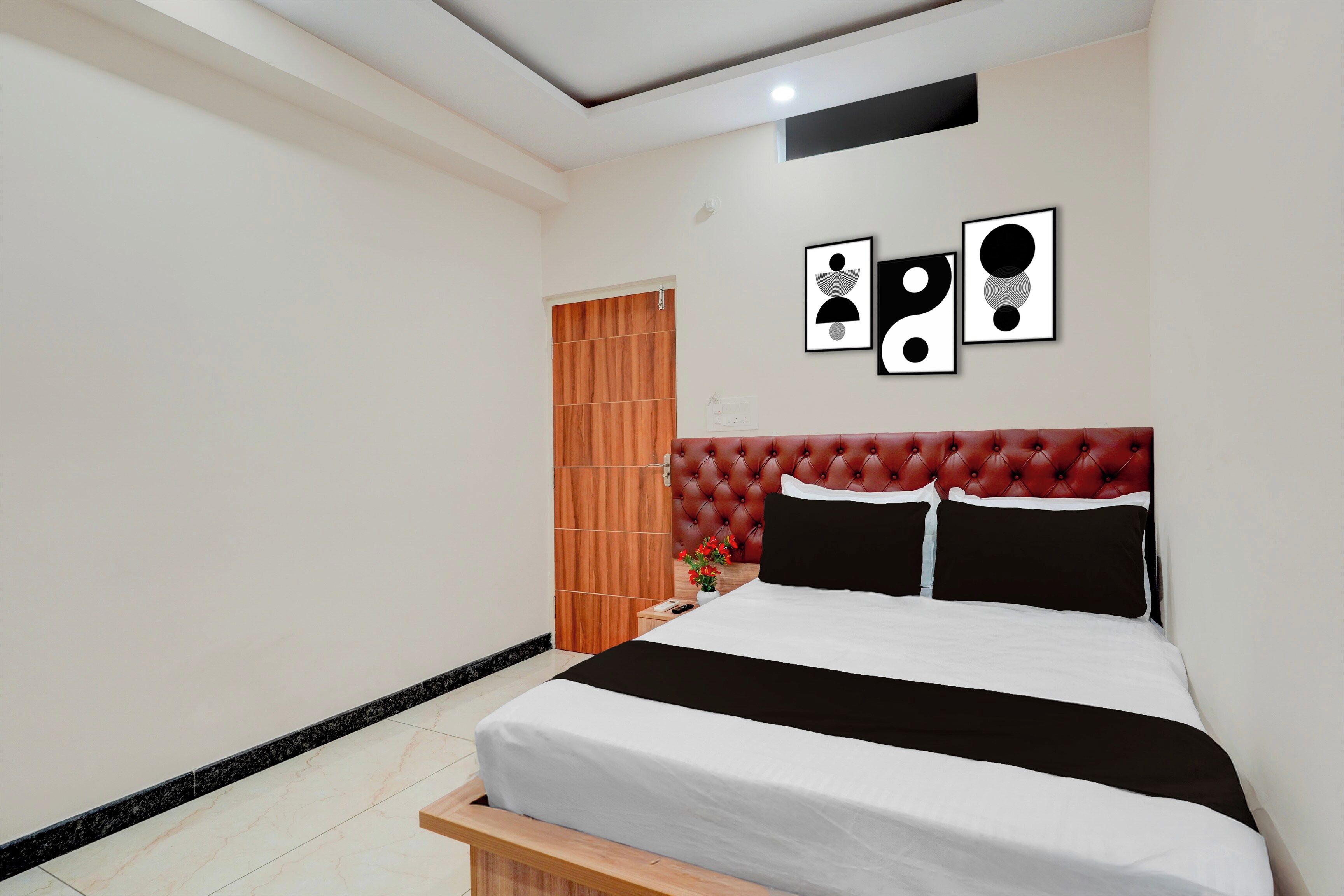 Ein Schlafzimmer mit einem Bett, einer Holztür und drei gerahmten Kunstwerken an der Wand.