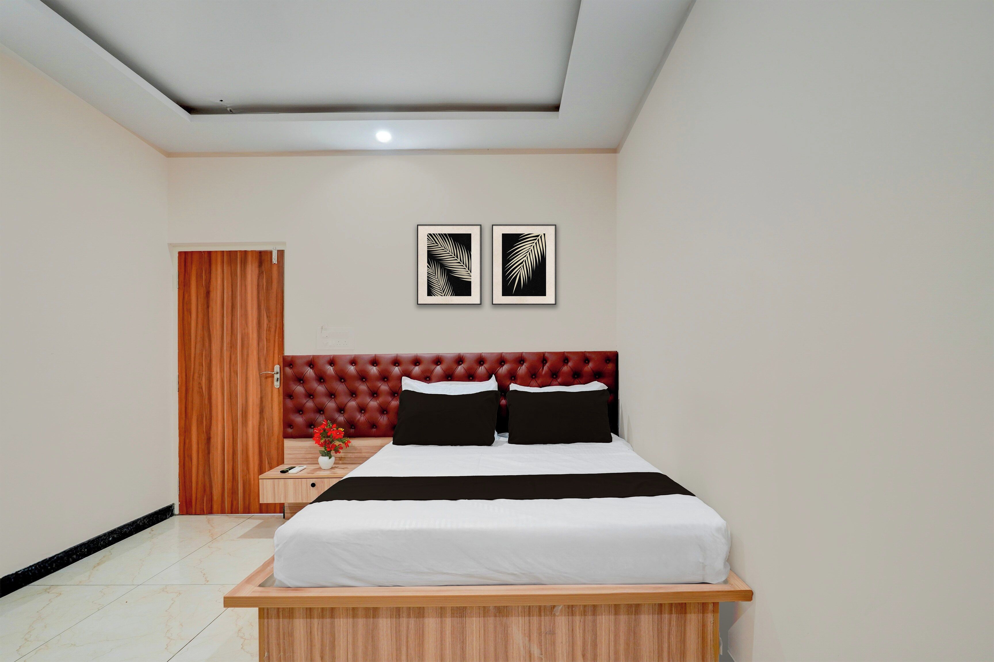 A bedroom with a bed, a nightstand, a wooden door, and two framed wall art pieces.