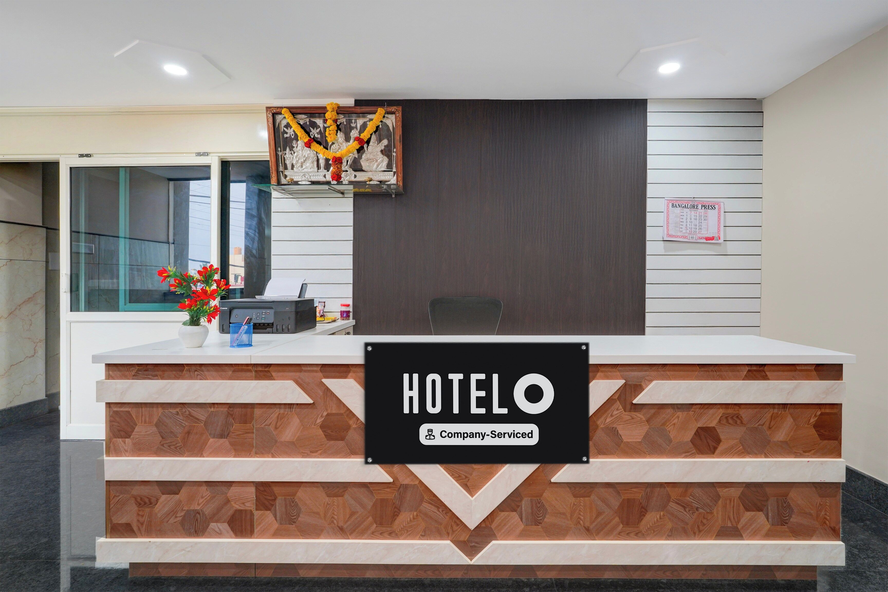 Un comptoir d’accueil d’hôtel avec une enseigne indiquant « HOTELO » et « Service aux entreprises ».