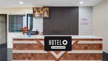 Un comptoir d’accueil d’hôtel avec une enseigne indiquant « HOTELO » et « Service aux entreprises ».