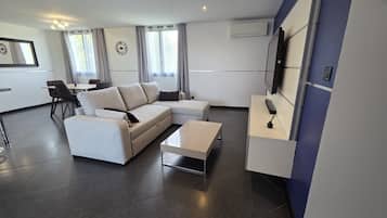 Un salon moderne avec un canapé, une table basse et un téléviseur fixé au mur.