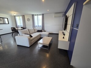 A modern living room with a sofa, coffee table, and a TV mounted on the wall.