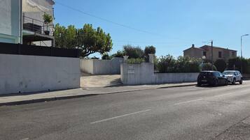 Une rue avec un immeuble blanc, une voiture noire et une voiture blanche garées sur le bord.