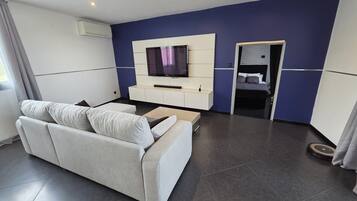Ein modernes Wohnzimmer mit einer Couch, einem Flachbildfernseher und einem kleinen Beistelltisch.