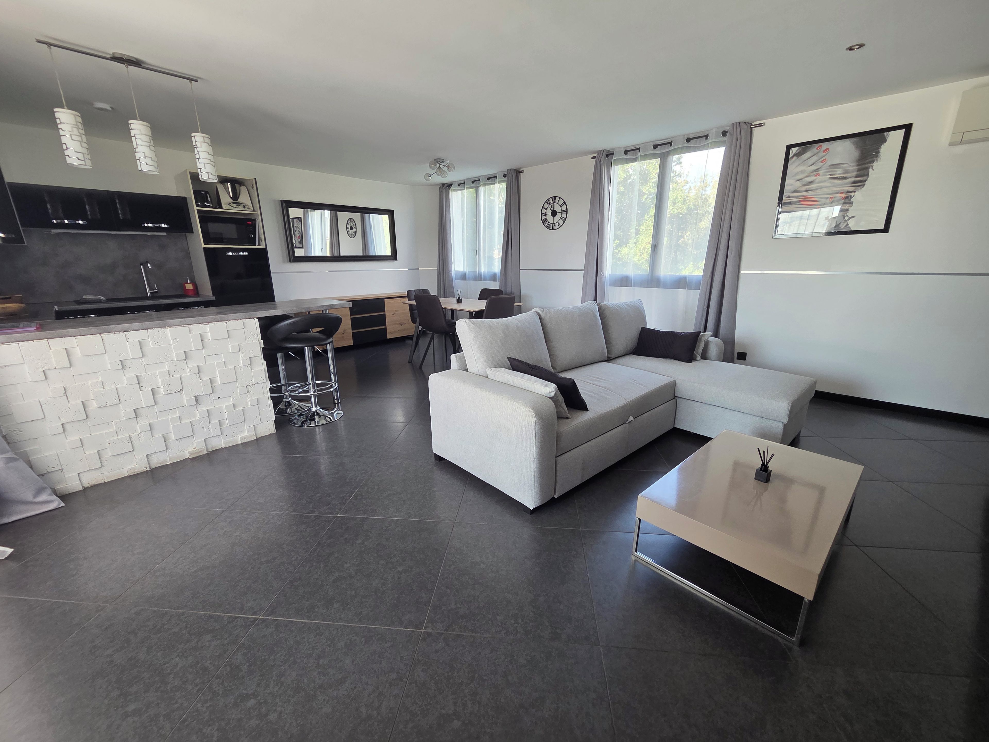 A modern living space with a kitchen, dining area, and seating.
