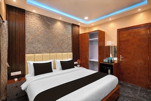 Ein Hotelzimmer mit einem großen Bett, einem Schrank, einem Spiegel und einem kleinen Tisch mit Wasserkocher und Tassen.