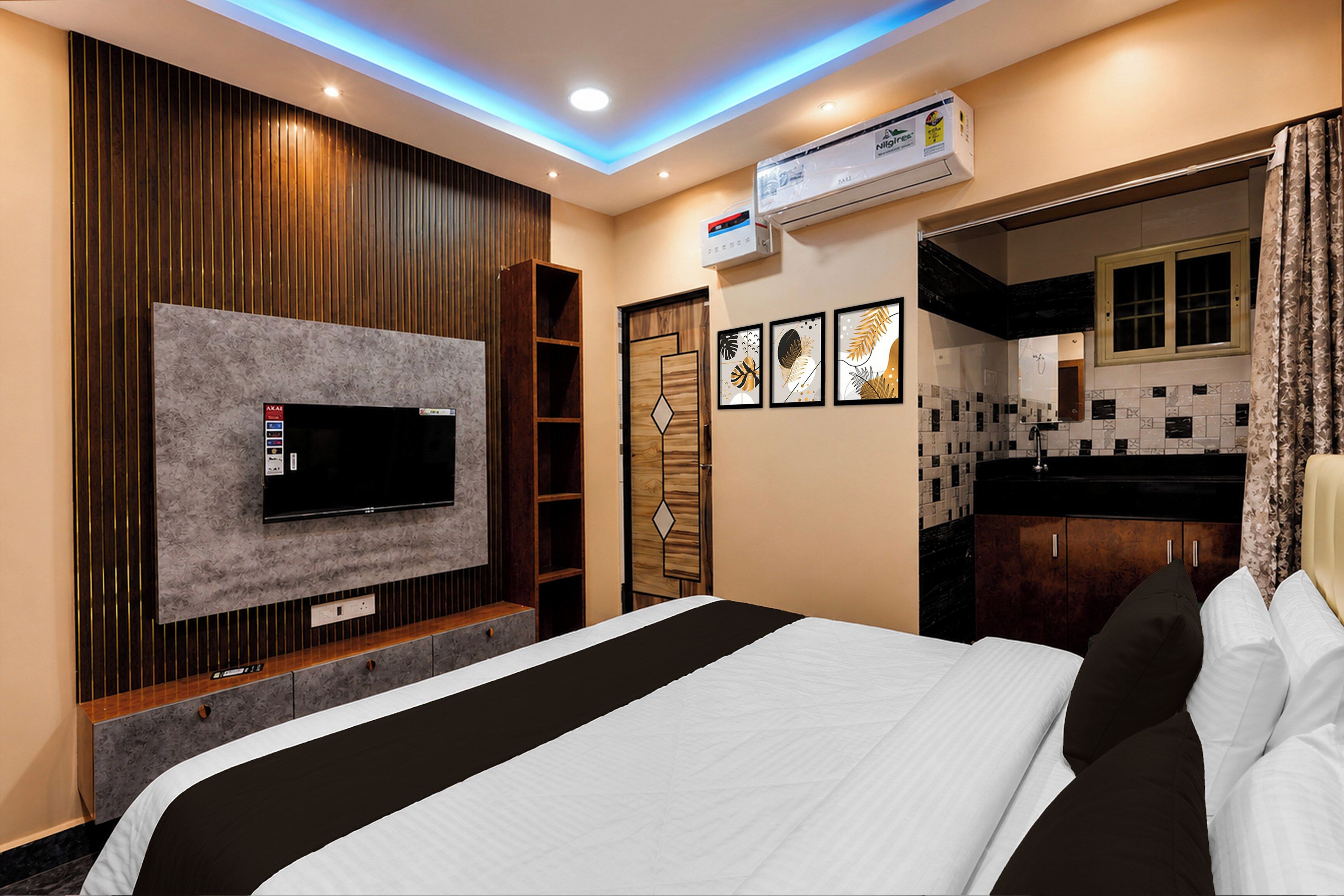 Habitación de hotel con cama, televisor de pantalla plana montado en la pared, armario, baño con ducha y kitchenette.