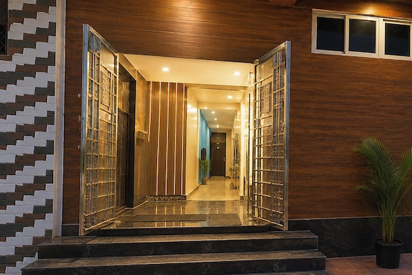 A modern building entrance with a glass door, a staircase, and a potted plant.