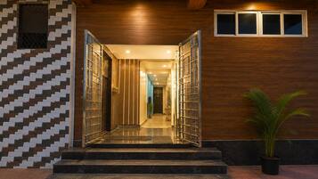 A modern hotel entrance with a wooden ceiling, a patterned wall, and a staircase leading to the interior.