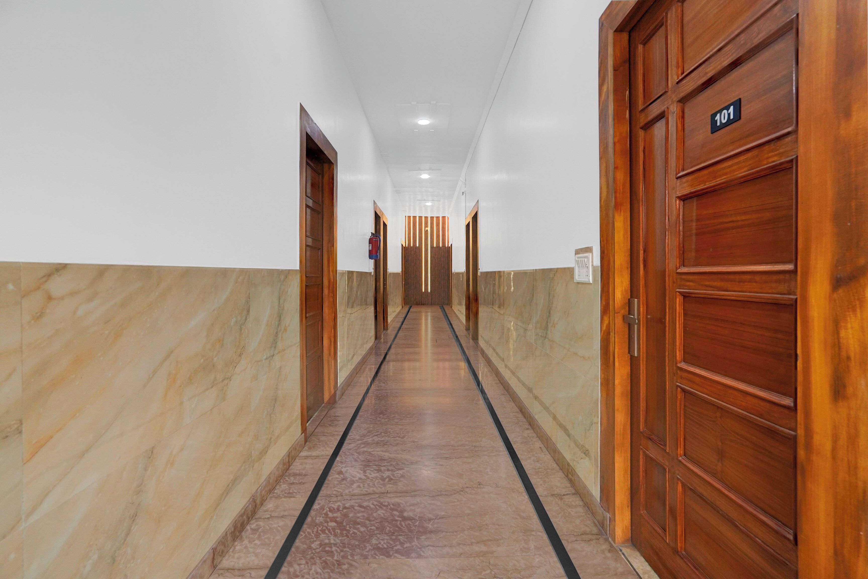 Un pasillo con puertas de madera, un extintor y un cartel que indica la habitación 101.