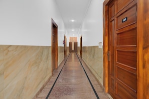 A hallway with wooden doors, a fire extinguisher, and a sign indicating room number 101. - Super Hotel O Chhatrapati Shivaji (Meerut)