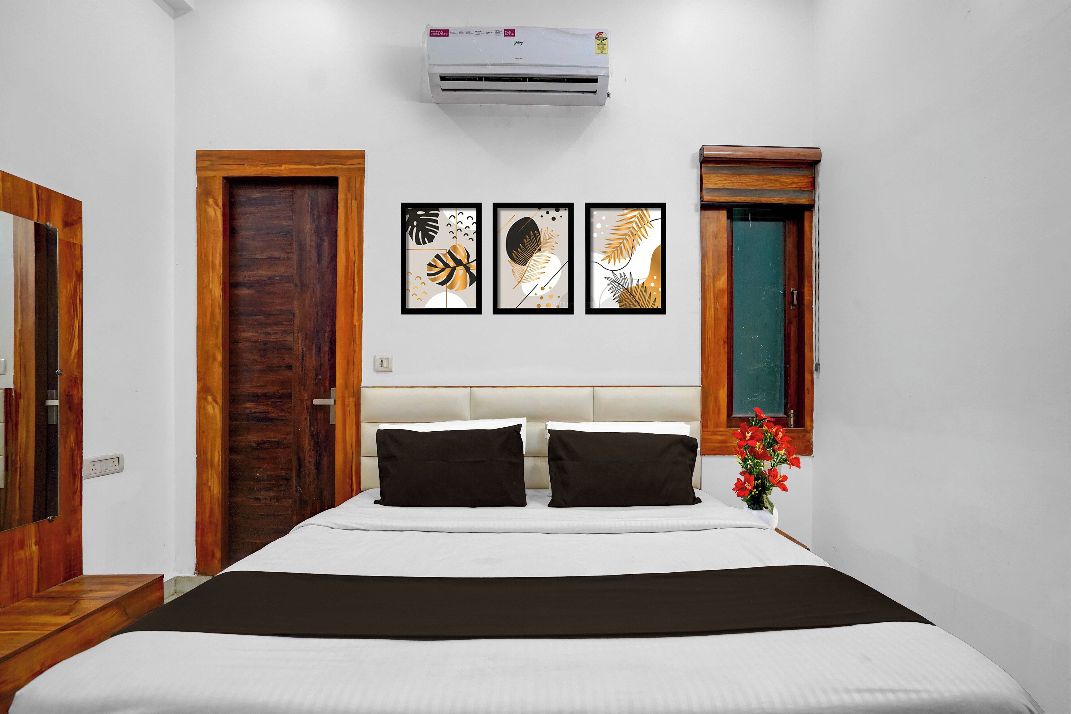 Quarto com cama, ar condicionado fixado na parede, porta de madeira e janela com vista.