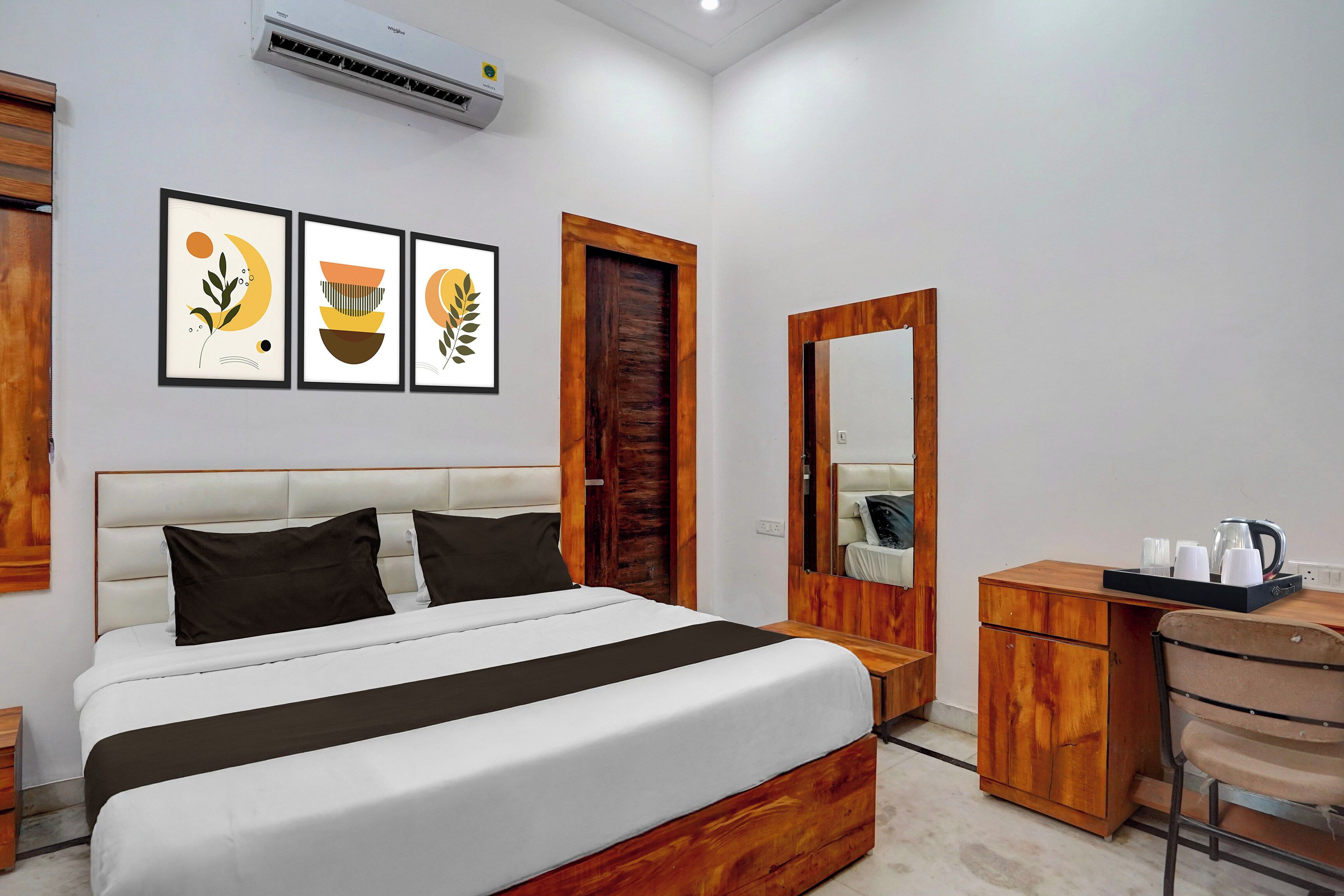 Una habitación de hotel con cama, escritorio, silla, espejo y decoración en la pared.