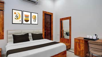 Una habitación de hotel con cama, escritorio, silla, espejo y decoración en la pared.