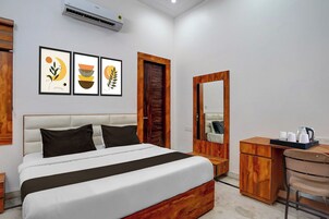 A hotel room with a bed, a desk, a chair, a mirror, and wall art.