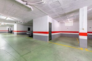 Een parkeergarage met betonnen muren, genummerde parkeerplaatsen en een groene vloer.