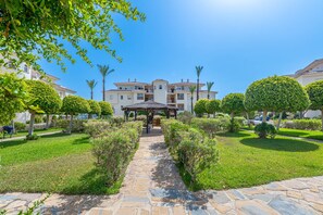 A courtyard with a gazebo, a stone pathway, and a building with multiple balconies. - Spectacular Mijas 3 bedroom Apartment with Large T (Mijas Costa)