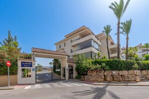 A multi-story hotel with a gated entrance, palm trees, and a clear blue sky. - Spectacular Mijas 3 bedroom Apartment with Large T (Mijas Costa)