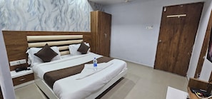 Una habitación de hotel con cama, cabecero de madera, mesita de noche y armario.