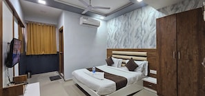 Una habitación de hotel con cama, armario, televisión, aire acondicionado y ventilador de techo.