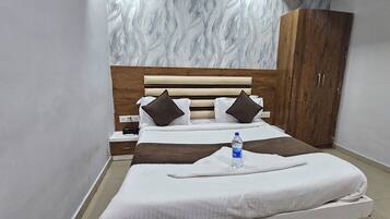 A hotel room with a bed, a wardrobe, a nightstand, and a water bottle.