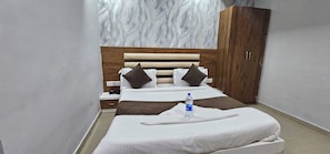 Una habitación de hotel con una cama, un armario, una mesita de noche y una botella de agua.