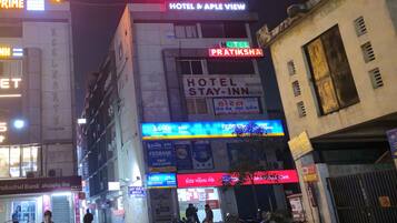 A hotel named 'Hotel Pratiksha' with a sign indicating 'Hotel Stay-In Rooms' and 'Hotel Stay-In Rooms' in another language.