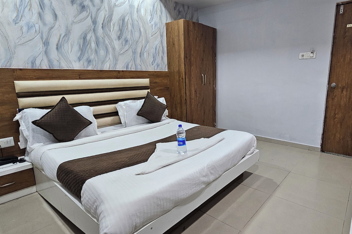 Una habitación de hotel con una cama, una mesita de noche, un armario y un televisor.