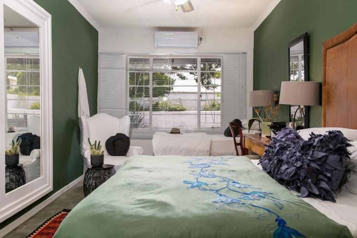 Un dormitorio con cama, una silla, un escritorio y una ventana con persianas.