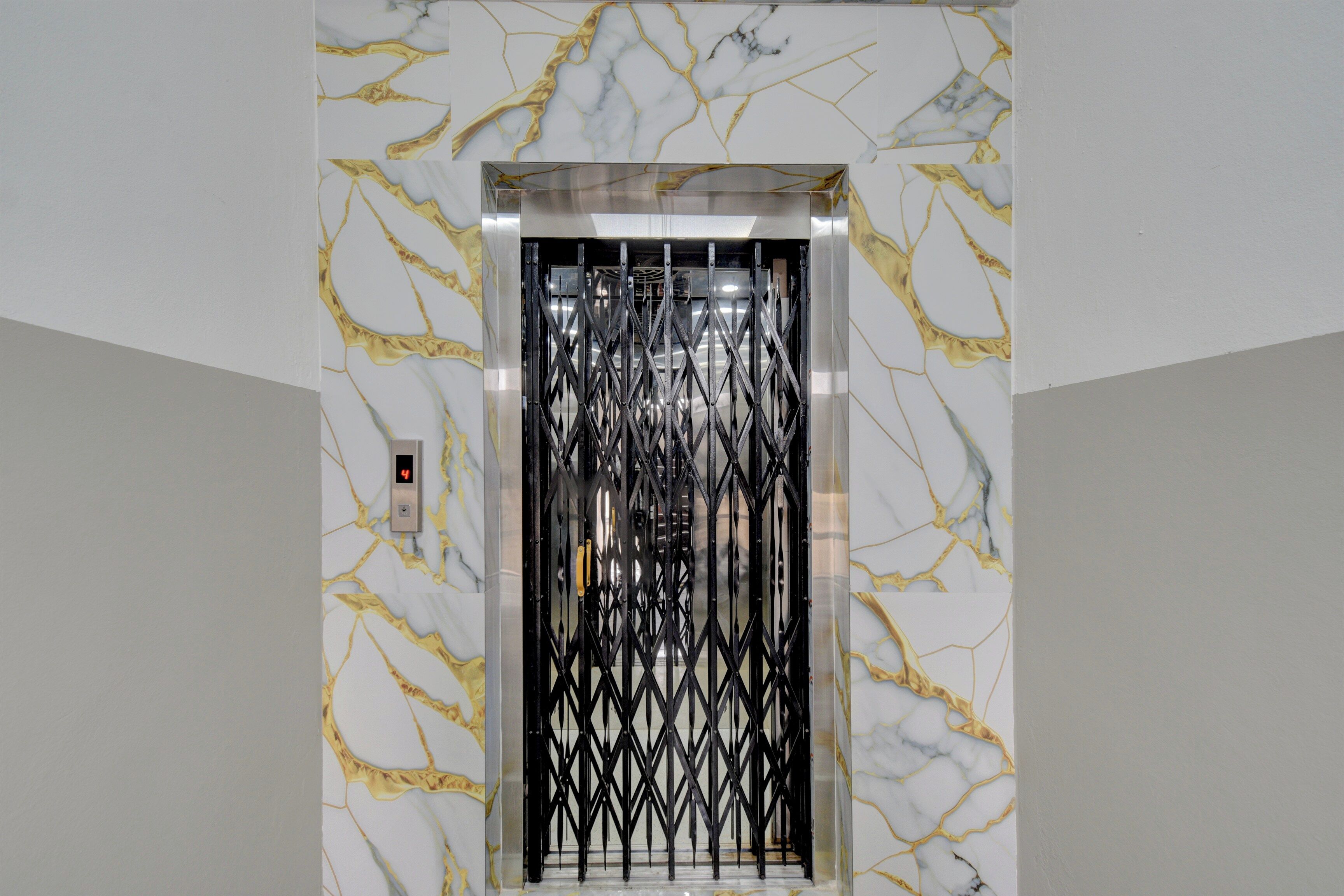An elevator with a marble wall design and a black metal gate.