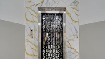 An elevator with a marble wall design and a black metal gate.