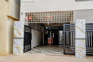 Entrada de un edificio con suelo a cuadros, puertas metálicas y un emblema decorativo sobre la entrada.